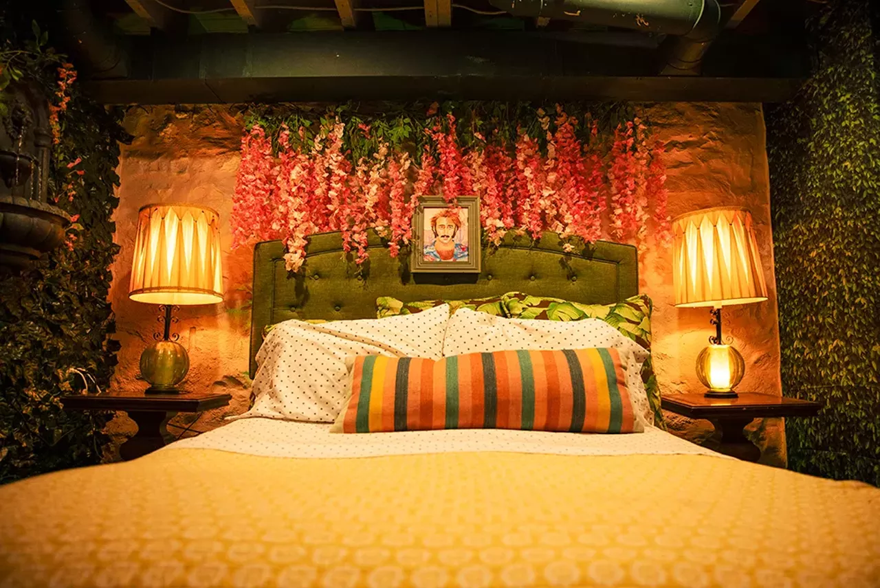 The basement bedroom feels like an Italian courtyard, with walls lined with green vines and pink flowers. Above the bed is Cage’s iconic mugshot from his 1987 film Raising Arizona.