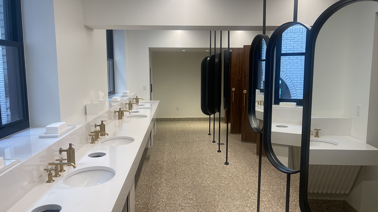 21c Museum Hotel The unisex lobby bathrooms at 21c Museum Hotel (1528 Locust Street) are where it's at. This spacious bathroom is so clean it's insane, but the real show stoppers are the oval mirrors giving the bathroom its own art piece and the natural lighting. The dark, wood-looking stalls are a nice contrast to the bright white walls and countertops. The gold handles, sink fixtures and soap dispensers as well as the paper towels atop a ceramic plate giving the bathroom a high-end feel.