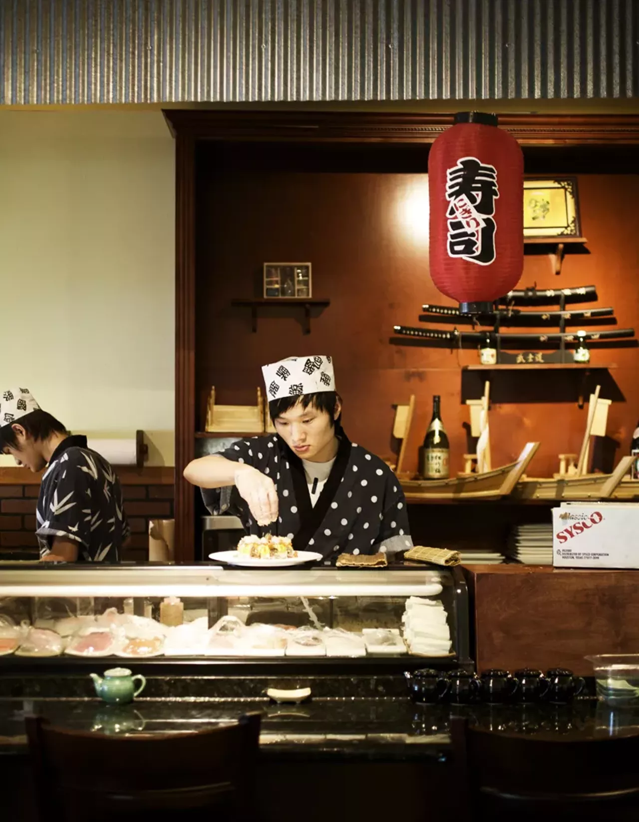Sushi chef Qi Dong at work while his cousin, and one of the owners of the restaurant, Jake Dong is working at the other counter behind the sushi bar.