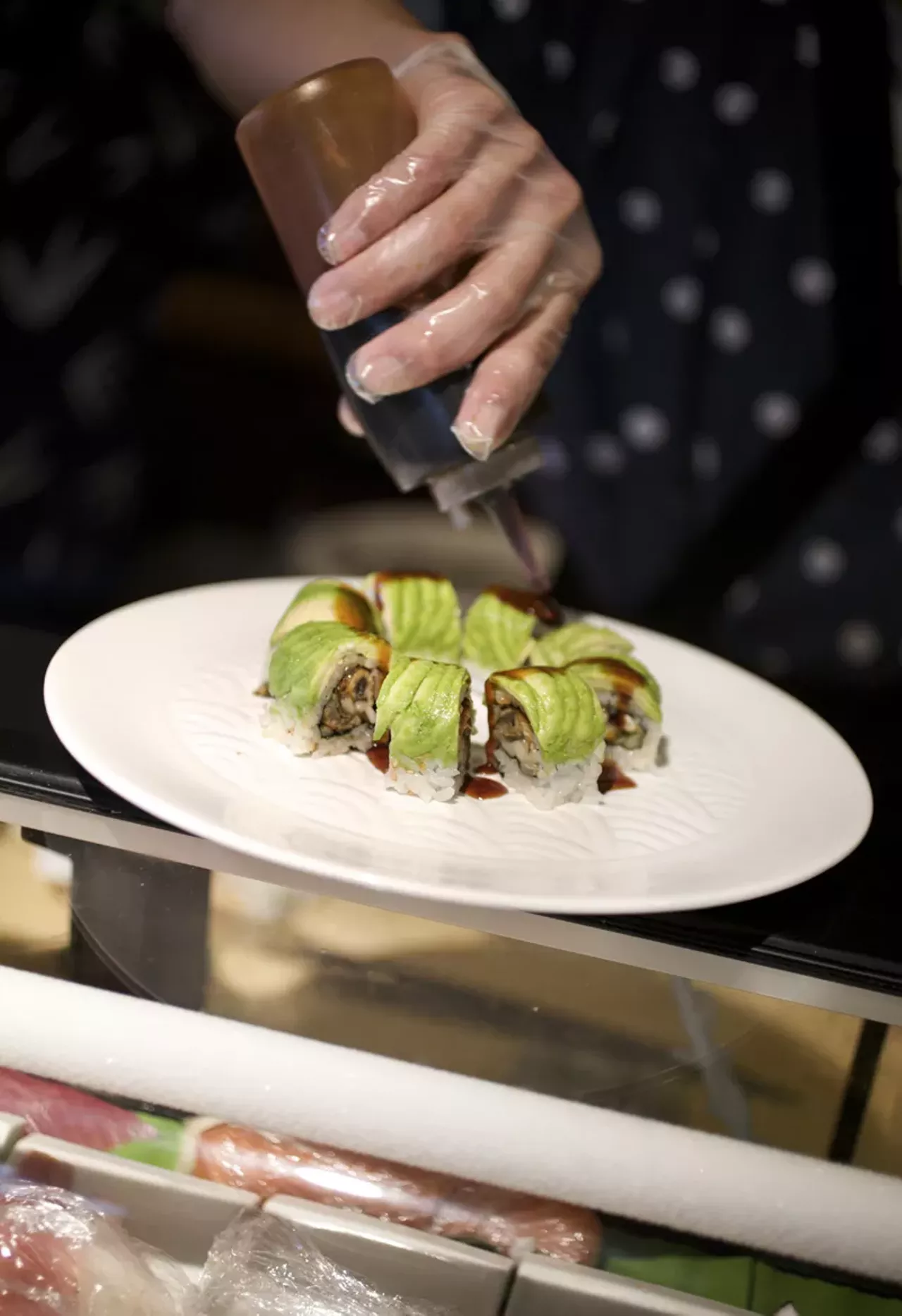 Qi Dong, after having rolled the Green Dragon Roll, continues to build the plate.