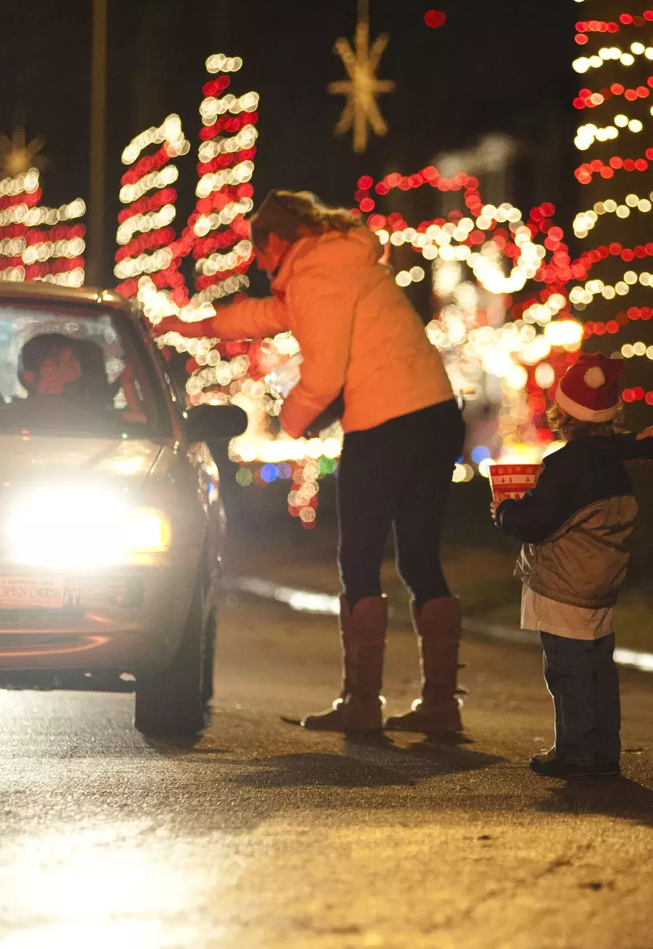 Mary Elliott and Tyler Kern, 5, accept donations and give candy canes to drivers passing through "Candy Cane Lane" on Wednesday night in South City.