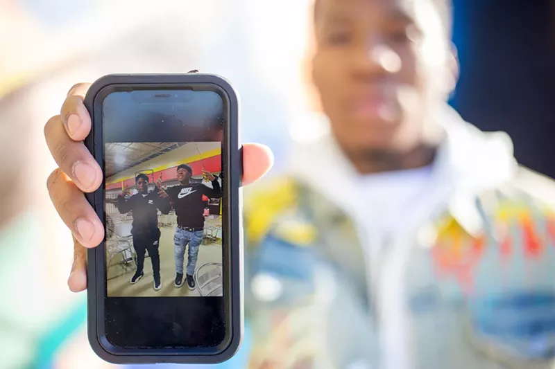 A man holds out an image on a phone screen.