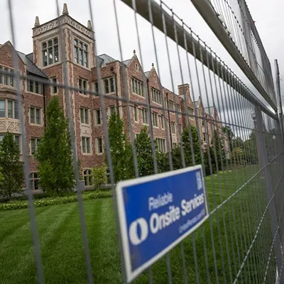 Bixby Hall on Wash U’s Danforth Campus towers over a metal fence surrounding the campus.