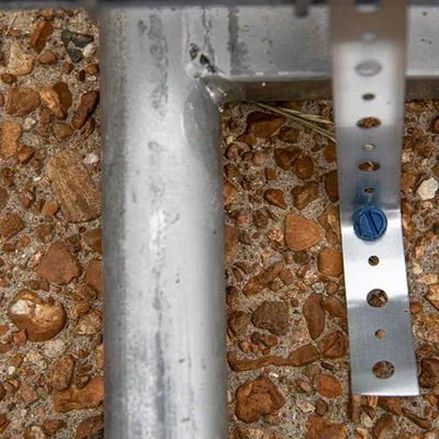 Screws bolt the metal fence surrounding Wash U’s campus into a sidewalk along Skinker Boulevard.
