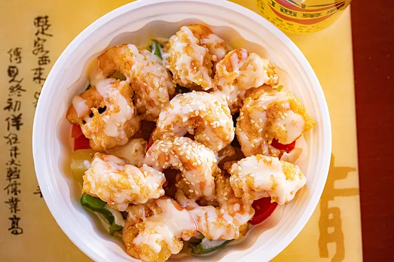 Pineapple shrimp is served with onion, bell pepper and mayo sauce.